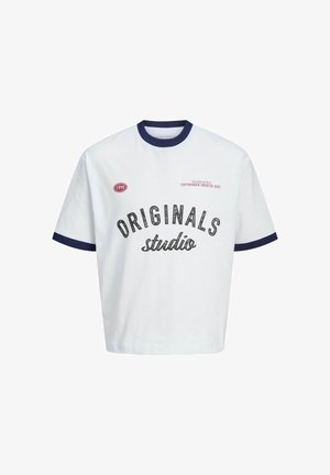 Witte t-shirt met marineblauwe geribde kraag en mouwen, met zwarte tekst "ORIGINALS studio." Samengevoegd met losse blauwe jeans en beige sneakers.