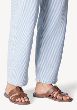 Sandales marron avec un design à plusieurs lanières, semelle plate et bout ouvert. Associées à un pantalon rayé bleu clair avec des jambes droites.
