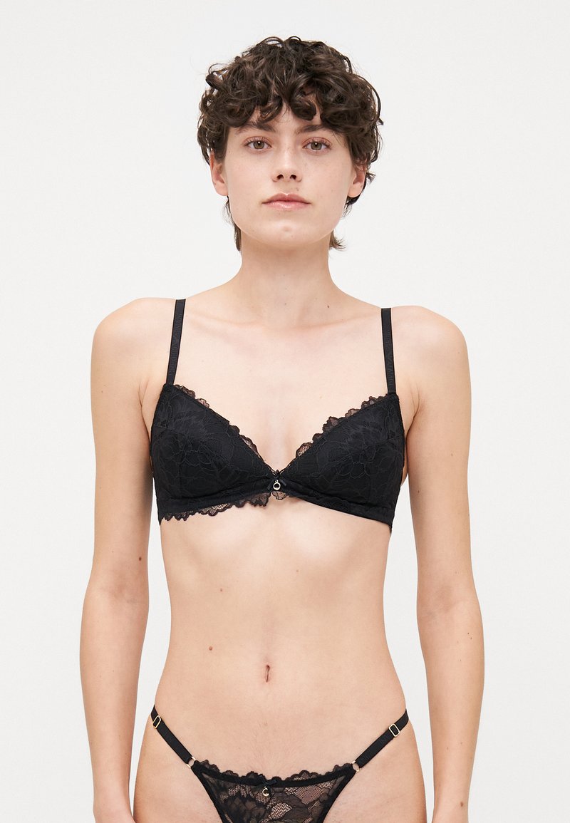 Black lace bra with triangular cups, scalloped edges, and a center button detail. Features thin adjustable straps and a delicate pattern.