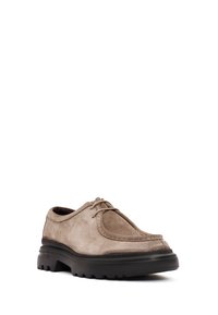 Chaussures en daim de couleur beige, bout rond et à lacets. Semelle en caoutchouc noir épais avec des sculptures pour une meilleure adhérence.