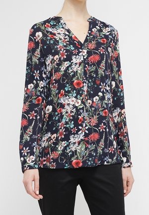 Blusa floreale in tessuto blu navy, con scollatura a V, maniche lunghe e un vivace mix di fiori in rosso, bianco e verde. Texture morbida.