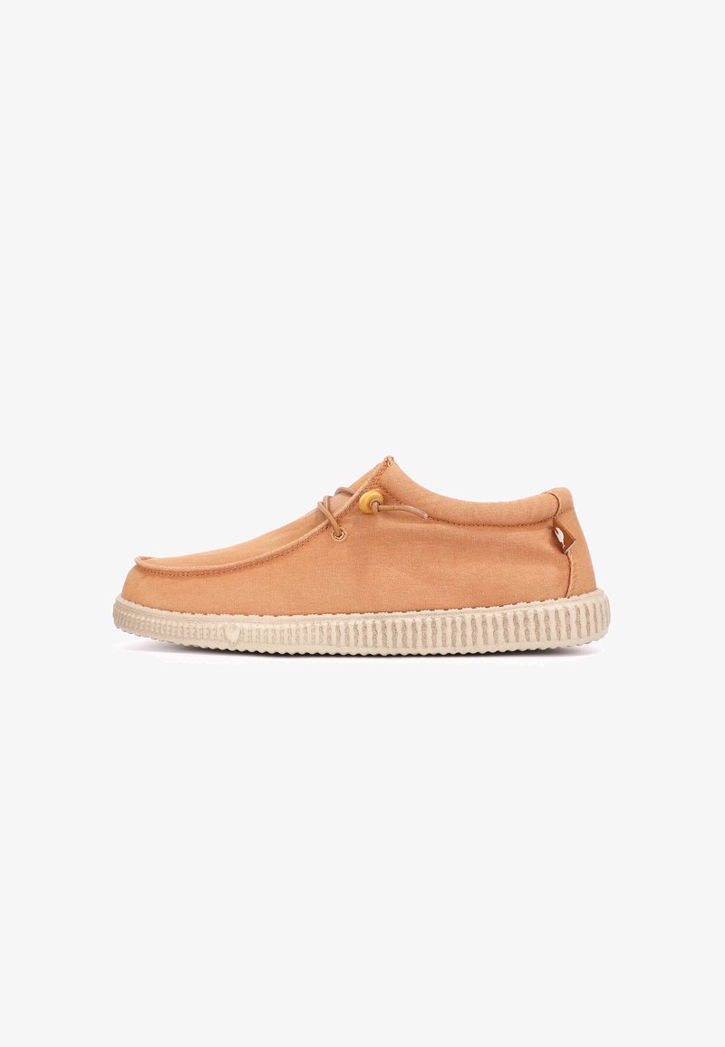 Chaussure décontractée beige avec semelle beige rainurée profilée basse, tige en tissu et détail de lacets près de la cheville, vue de côté.