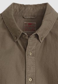 Bruine button-up shirt met kraag en bovenste knopen vastgemaakt, met een zichtbare Levi's-label binnenin de kraag.