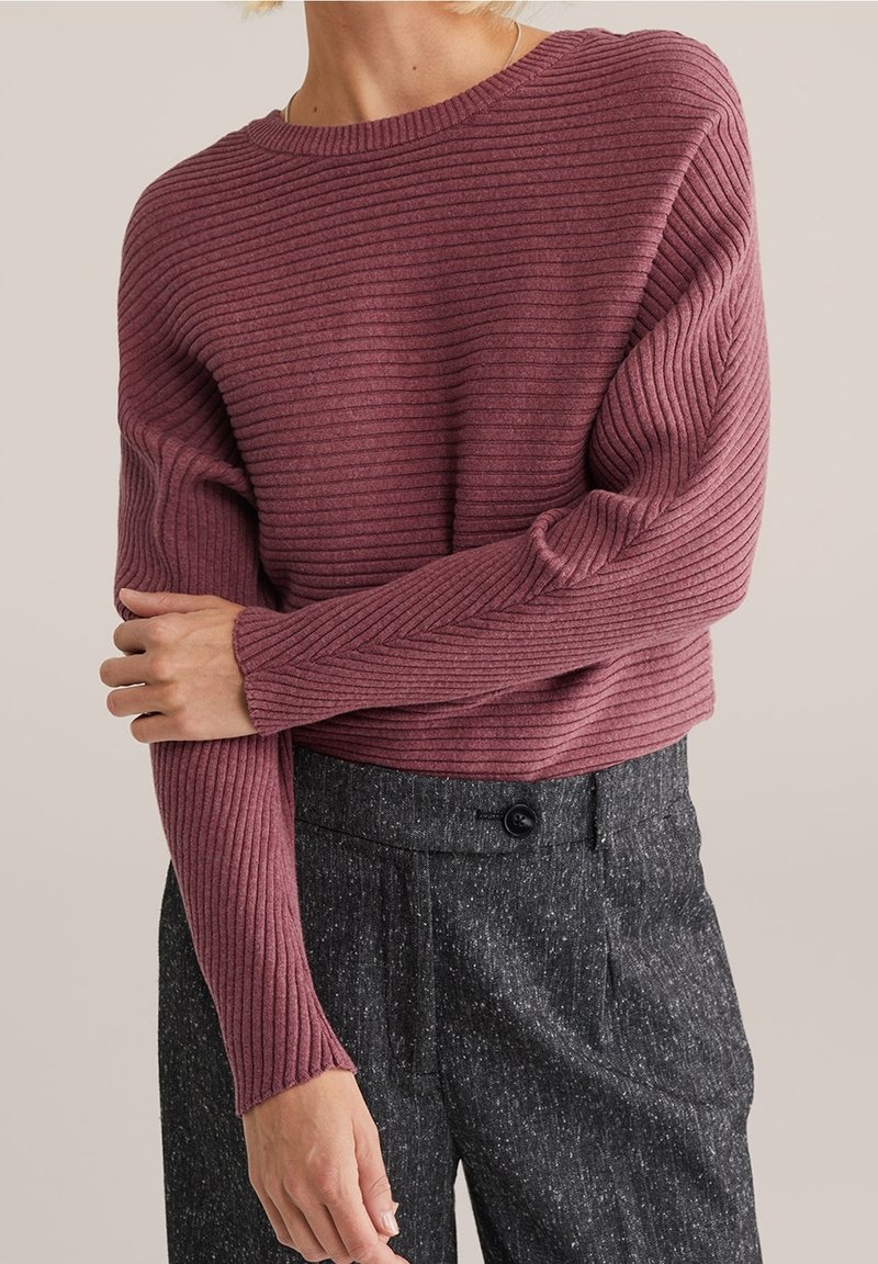 Žebrovaný zkrácený svetr v tmavě bordó barvě, doplněný texturovanými tmavě šedými kalhotami s knofl íkovým zapínáním. Měkký pletený materiál s dlouhými rukávy.