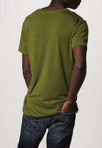 Oliven grøn t-shirt med rund hals og korte ærmer, lavet af blødt stof. Kombinationen med mørkeblå denim jeans, der har en afslappet pasform.