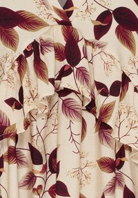 Blomsterkjole med en cremet baggrund og maroon- og guldblade. Volang-halsudskæring og struktureret stof fremhæver det botaniske mønster.