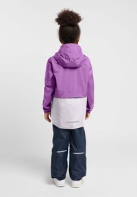Paarse hoodie jack met een witte onderkant, gecombineerd met marineblauwe broek. De jas heeft elastische manchetten en reflecterende accenten.
