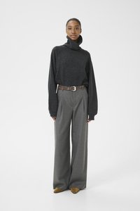 Dark gray knitted turtleneck sweater with relaxed fit, paired with light gray wide-leg trousers and a patterned belt. Brown pointed shoes.