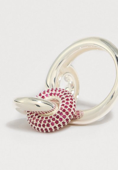 Bague en argent au design torsadé avec un détail texturé orné d'une pierre rose rappelant un serpent enlacé dans l'anneau.