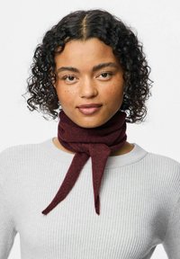 Bordo vilnonis šalikas, surištas mazgu, dėvimas ant šviesiai pilkos nertinės megztos palaidinės. Lygus paviršius, vidutinio pločio ir pailgos formos.