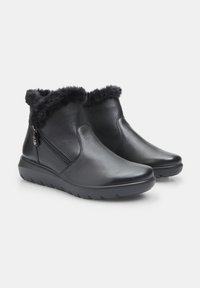 Botas de tobillo de cuero negro con un acolchado de piel sintética, cremallera lateral y suela de goma texturizada para mayor agarre. Acabado suave y punta redondeada.