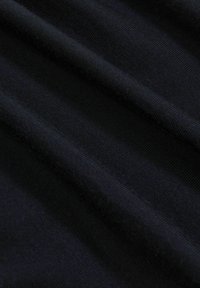 Tessuto nero con una superficie texturizzata, caratterizzato da motivi lisci e rigati, drappeggiato e piegato per enfatizzare la morbidezza del materiale.