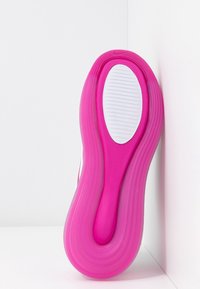 Semelle de chaussure présentant un design en caoutchouc rose avec des rainures texturées, une semelle intermédiaire blanche et une forme arrondie, positionnée sur un fond blanc.