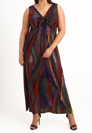 Vrouw draagt een mouwloze, meerkleurige maxi-jurk met patroon en een knoopdetail vooraan, met zwarte sandalen met hoge hakken.