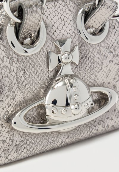 Ασημί τσαντάκι με υφή και λεπτομερή ασημένιο έμβλημα που απεικονίζει έναν σταυρό, σφαίρα και δαχτυλίδι κοντά στις προσδέσεις των λουριών.