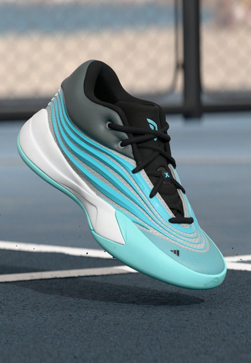 Tyrkysová a čierna športová teniska s čiernymi šnúrkami levituje nad vonkajším športovým ihriskom s bielymi čiarami a pozadím z reťazového pletiva.