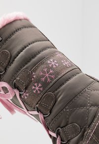 Botas de neve castanhas acolchoadas com acabamento em pele sintética rosa, padrão de flocos de neve e atacadores rosa; apresentam tiras reforçadas e ferragens resistentes.