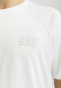 Valge lühikeste varrukate spordipluus tekstuuriga kangast. Ees on peen hall "CNZ" logo rinnapiha piirkonnas.