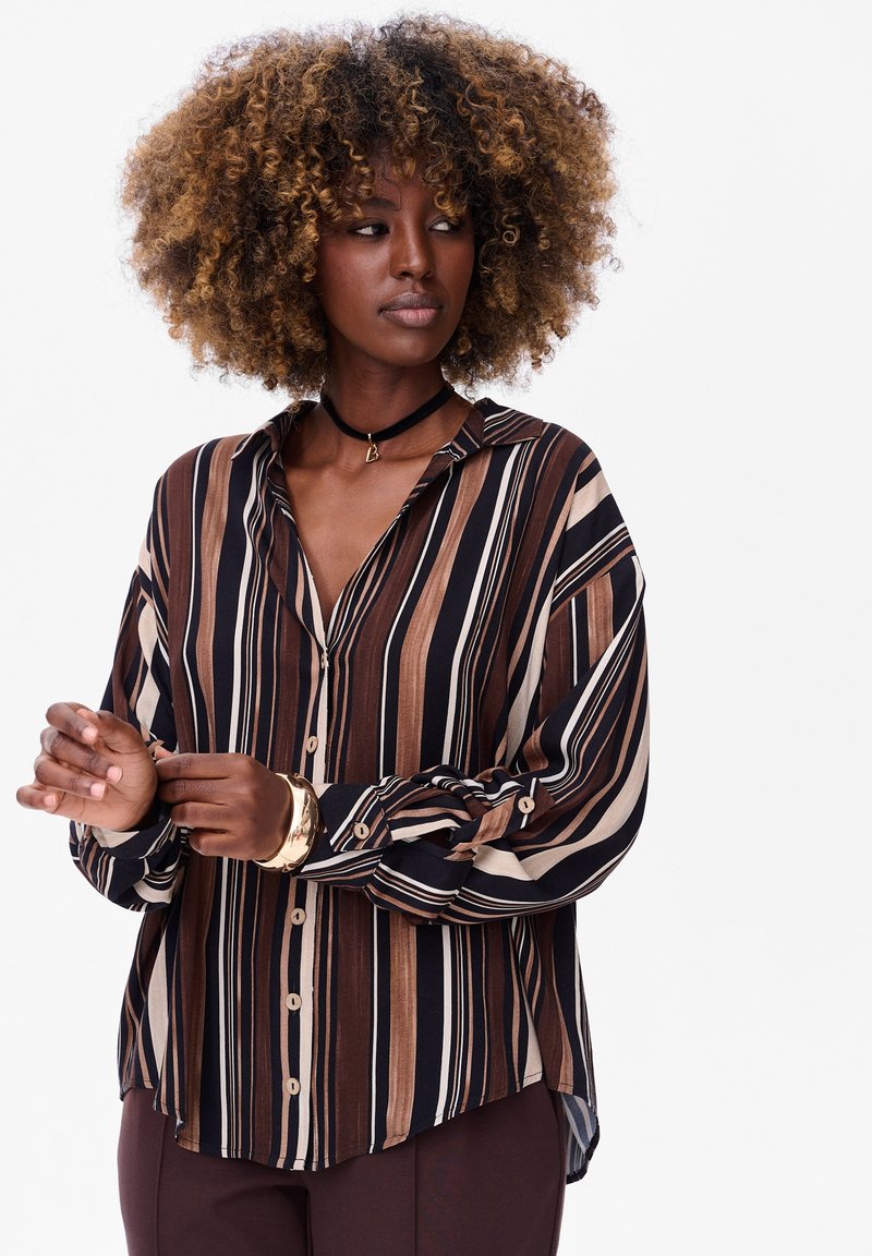 Striped button-up shirt in brown, cream, and navy, featuring a collar, long sleeves, and a relaxed fit with a curved hemline.