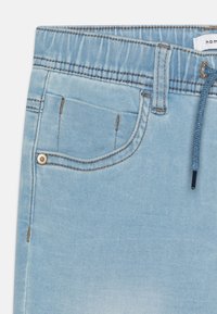 Svijetloplavi traper šorc s elastičnom waistband-om, vezicom, prednjim džepom i kontrastnim šavovima. Mekana, izblijedjela tekstura.