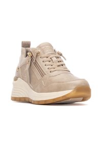 Zapatilla de ante beige con una suela blanca gruesa. Presenta detalles de cremallera, parte delantera con cordones y acentos texturizados. Diseñada para la comodidad y el soporte.