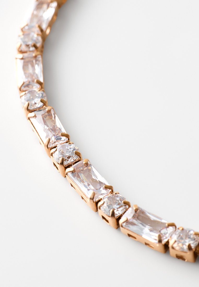 Collana in tono oro rosa con accenti di cristalli trasparenti rettangolari e rotondi in un design a catena, che mette in mostra una superficie lucida e una texture brillante.