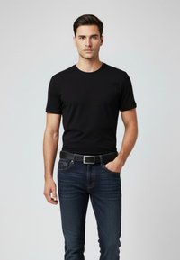 Schwarzes Baumwoll-T-Shirt mit Rundhalsausschnitt und kurzen Ärmeln, kombiniert mit dunkelblauen Denim-Jeans. Die Jeans haben ein klassisches Fünf-Taschen-Design und einen schwarzen Gürtel.