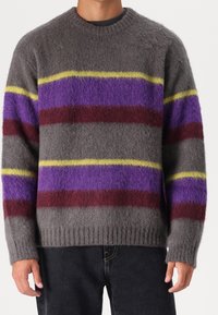 Maglione grigio a maglia con strisce orizzontali in viola, giallo e bordeaux. Polsini e fondo a coste. Texture morbida e pelosa.
