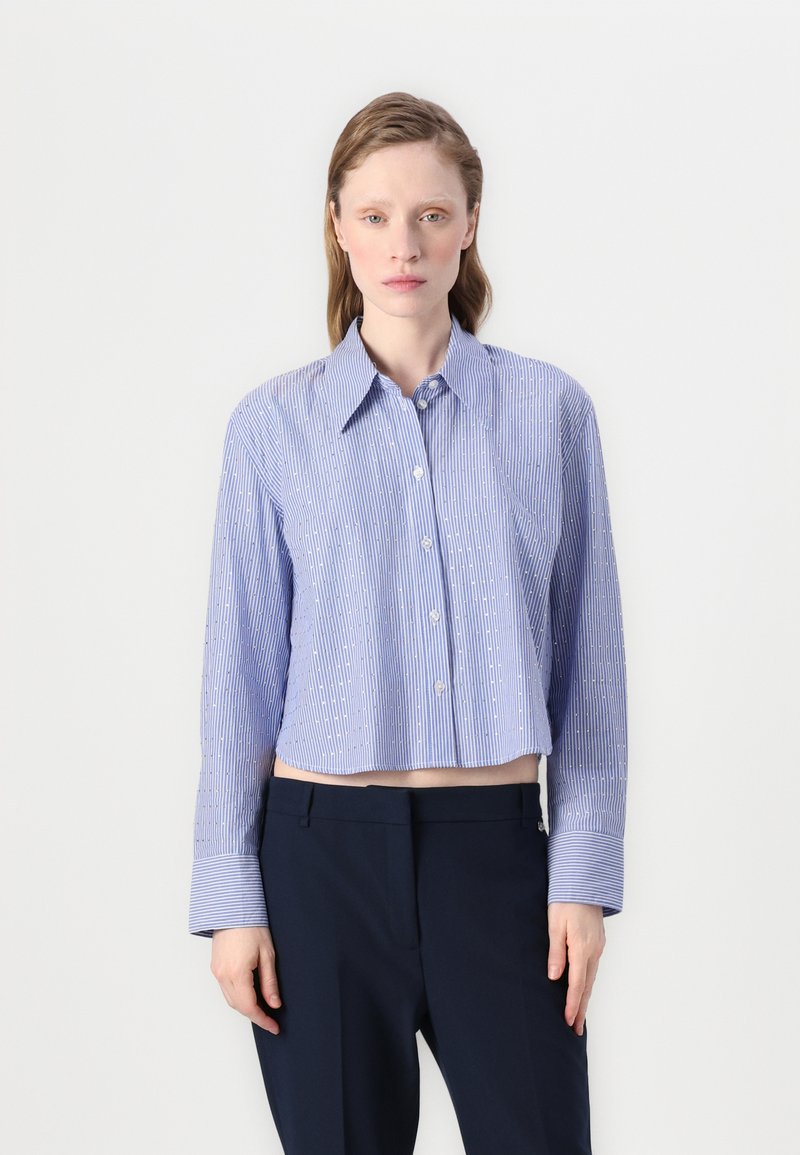 Blue and white striped, cropped button-up shirt with long sleeves and wide cuffs, made of lightweight fabric. Features a classic collar.