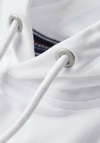 Felpa bianca con cappuccio e lacci con occhielli metallici argentati. Tessuto morbido con un interno a coste e un'etichetta interna in contrasto.