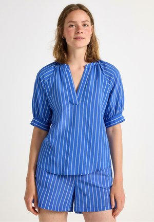 Blau gestreiftes Oberteil mit V-Ausschnitt und puffärmeligen Ärmeln, kombiniert mit passenden Shorts, alles aus einem glatten, leichten Stoff gefertigt.
