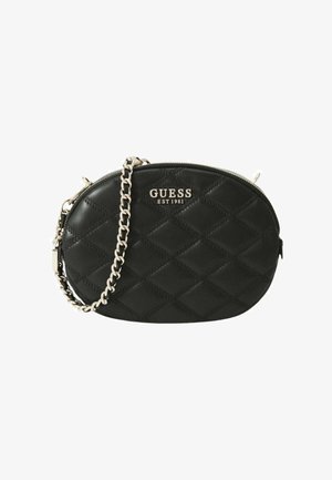Sac bandoulière ovale matelassé noir Guess avec chaîne argentée et fermeture éclair, avec le logo "GUESS EST 1981" sur le devant.