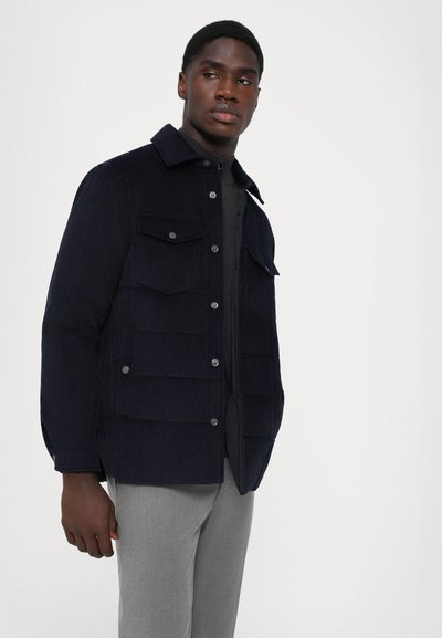 Navy Cordjacke mit Knöpfen, zwei Brusttaschen und zwei Seitentaschen, mit einem Kragen und strukturiertem Stofffinish.