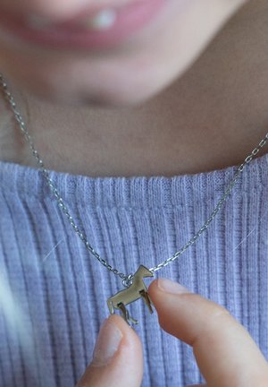 Zilveren ketting met een kleine, gedetailleerde paardenhanger. Hanger is van metaal met een gladde afwerking. Gekleed met een lavendel ribbeltop.