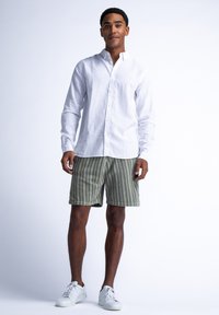 Witte linnen overhemd met knopen, groene gestreepte shorts en witte sneakers. De outfit heeft een ontspannen pasvorm en een casual ontwerp.