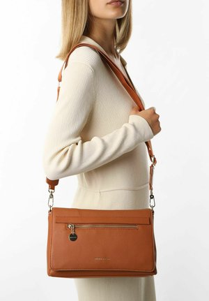 Sac de bandoulière en cuir tan avec une poche avant zippée, texture lisse et sangle ajustable, présenté sur un fond uni.