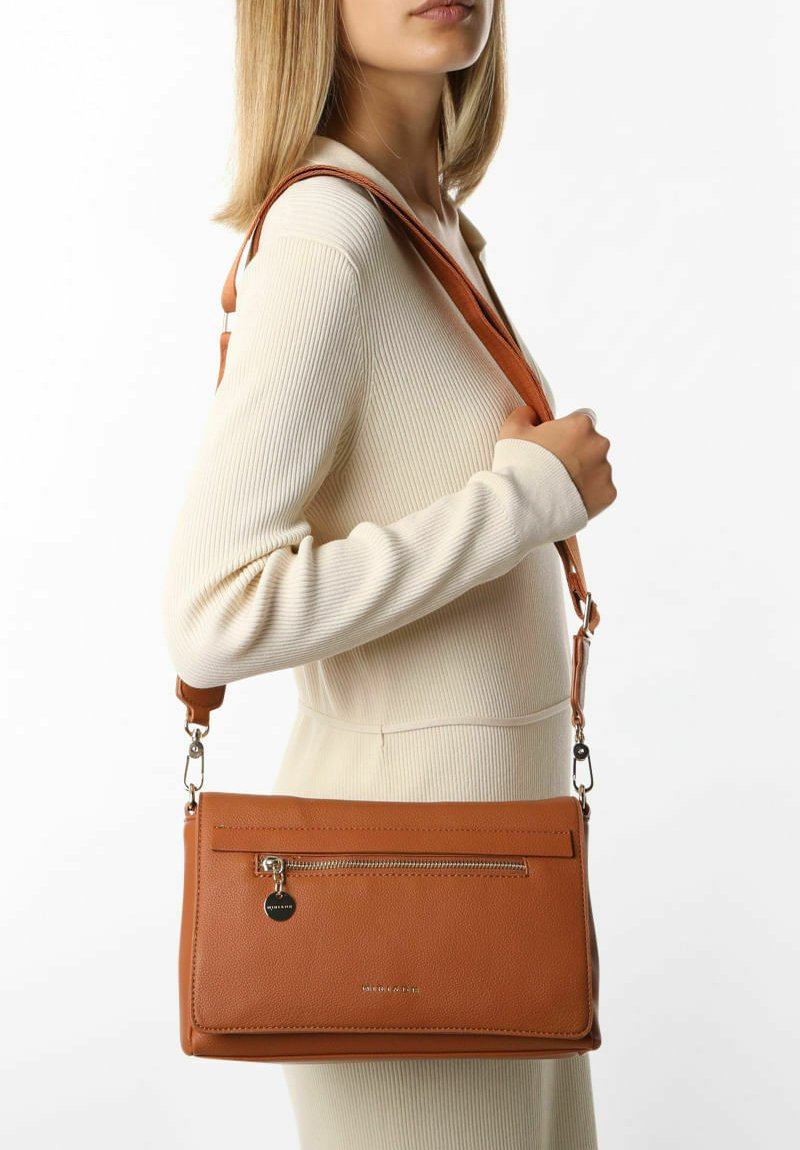 Tan læder crossbody taske med en lynlåslomme foran, glat tekstur og justerbar rem, vist mod en ensfarvet baggrund.