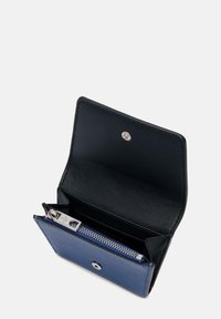 Portefeuille compact en cuir bleu et noir, avec une section pour les pièces zippée, un fermoir à pression et des surfaces lisses et texturées.