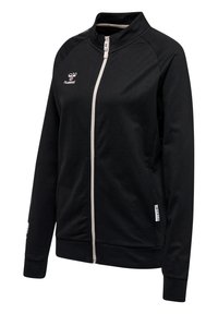 Svart zip-up-jacka med hög krage, kontrasterande vit dragkedja och liten logotyp på vänster bröst. Mjukt tyg med långa ärmar och muddar.