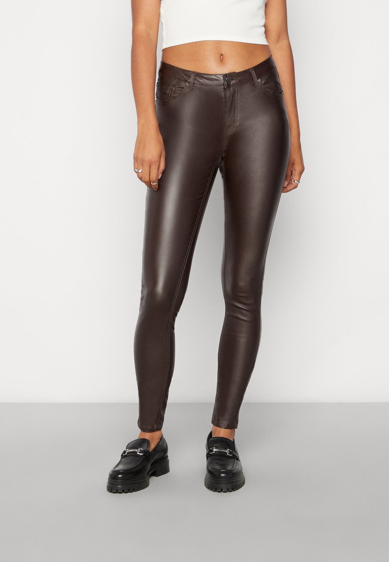 Pantaloni skinny in ecopelle marrone con una texture liscia, progettati con una vita a media altezza, cinque tasche e dettagli di cucitura minimi.