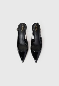 Scarpe da donna slingback in vernice nera con punta affilata, dotate di sottili cinturini e dettagli con fibbie dorate, su uno sfondo bianco.