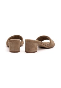 Mule aperte in camoscio beige con tacco basso a blocco e forma arrotondata; presenta una texture morbida e un design senza cuciture senza hardware visibile.