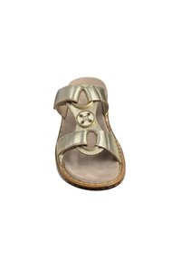Gold slide sandal with two wide straps, circular cutouts, and a decorative button; textured insole, rounded toe, and stitched edges.
