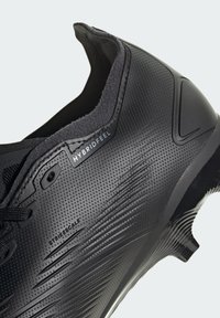 Scarpa da ginnastica nera con materiale testurizzato, design aerodinamico e dettagli in rilievo. Include elementi di branding per "Hybridfeel" e "Strikescale."