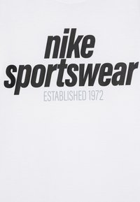 Λευκό βαμβακερό t-shirt με έντονο μαύρο κείμενο: "nike sportswear" και "ΙΔΡΥΘΗΚΕ 1972" σε μικρότερη γκρίζα γραμματοσειρά από κάτω.