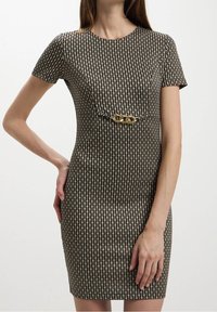 Robe à manches courtes noire et crème avec un motif et une silhouette ajustée ; elle comporte un accent en chaîne dorée à la taille. Texture lisse.