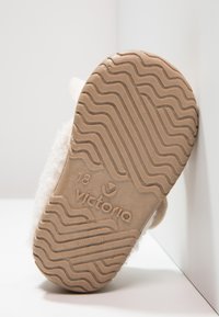 Semelle beige assez détaillée avec un motif de crampons ondulés. Présente la marque "Victoria" et la taille "18" en relief sur la surface.