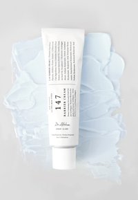 Hvit tube av Dr. Althea 147 Barrier Cream med en teksturert lys blå krembakgrunn. Emballasjen har svart trykk og en rund hette.