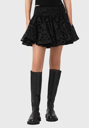 Sort nederdel med laserudskåret blomsterpatron, klokkeformet pasform og tekstureret stof, kombineret med knælange sorte læderstøvler.