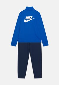 Zila garām piedurknēm augšdaļa ar baltu Nike logotipu uz aizmugures un tumši ziliem biksēm. Izgatavota no mīksta, elastīga materiāla; piedāvā augstu apkakli un elastīgas aproces.